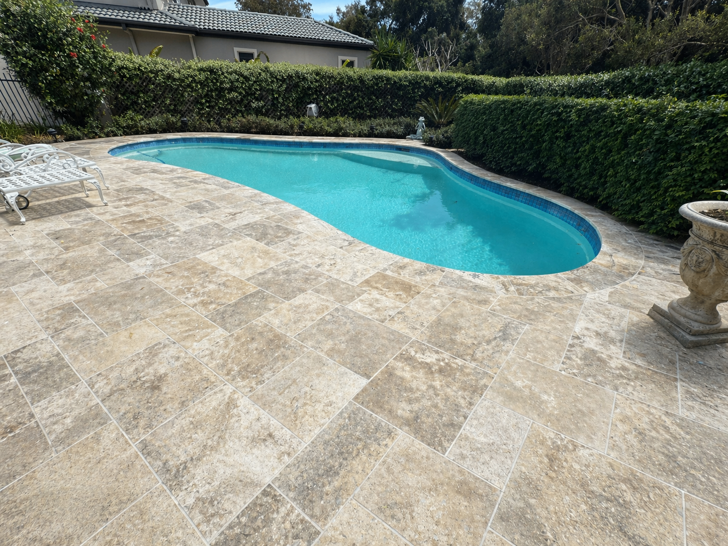 Freeform fibreglass pool with travertine paving